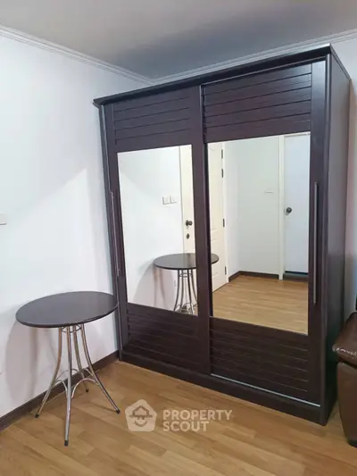 Spacious bedroom with elegant mirrored wardrobe and sleek round table