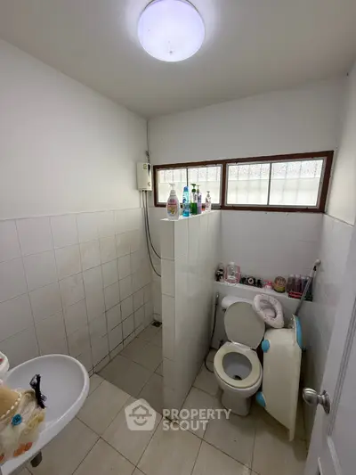 Compact bathroom with tiled walls and essential fixtures, ideal for small spaces.