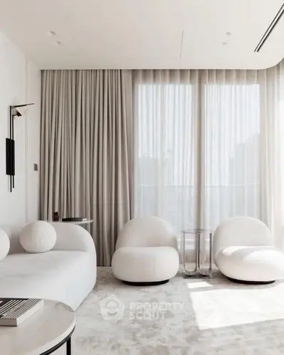 Modern living room with plush white furniture and floor-to-ceiling windows.