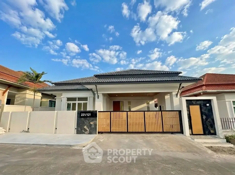 Charming single-story home with modern facade and gated entrance under a clear blue sky.
