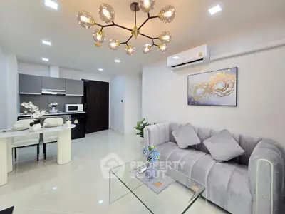 Modern living room with elegant chandelier and stylish kitchen in open layout