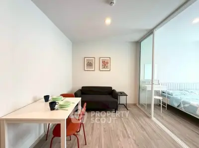 Modern apartment interior with cozy living room and adjacent bedroom, featuring stylish decor and wooden flooring.