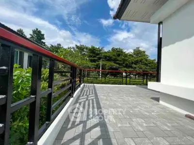 Spacious outdoor balcony with scenic garden view and modern railing design.