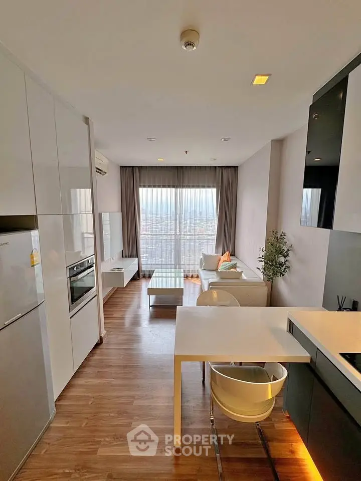 Modern open-plan living room with kitchen, featuring sleek design and city view.