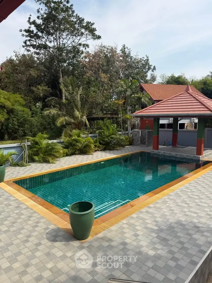 Stunning outdoor pool area with lush greenery and elegant pavilion, perfect for relaxation and entertainment.
