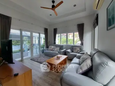 Spacious living room with modern decor and large windows offering garden views.