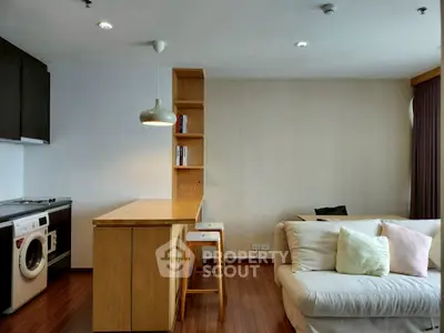 Modern living room with cozy sofa and stylish kitchen area featuring a washing machine.