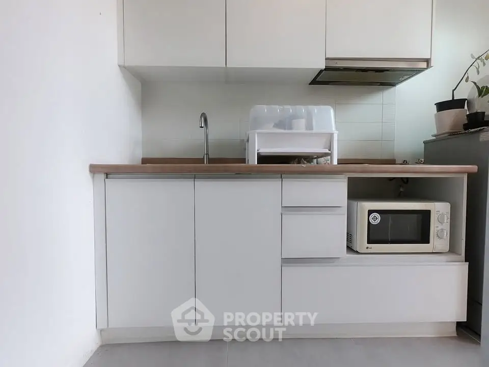 Modern minimalist kitchen with white cabinetry and built-in microwave