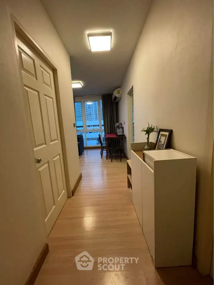 Modern apartment hallway leading to a cozy living area with city view.