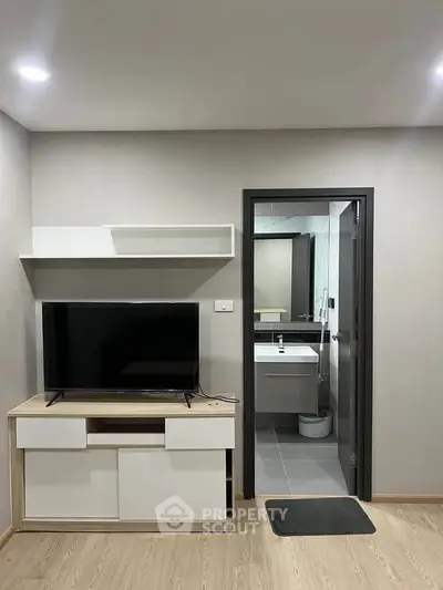 Modern living room with TV unit and view into a sleek bathroom