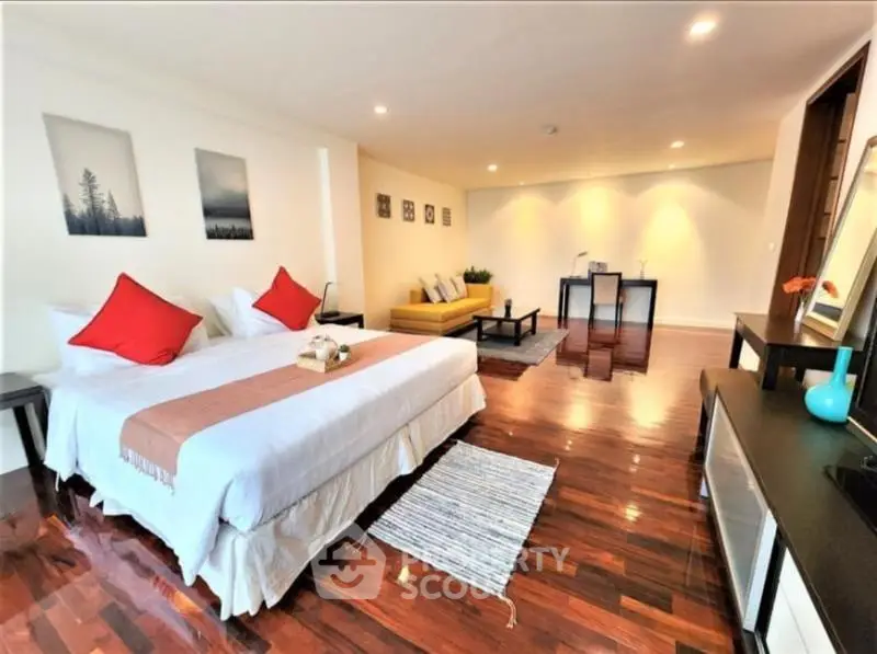 Spacious bedroom with elegant decor and hardwood floors in modern apartment.