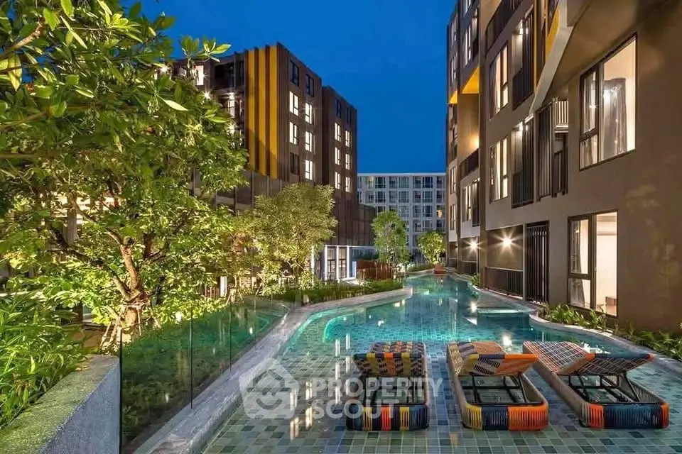 Luxurious modern apartment complex with stunning poolside view and lush greenery at night.