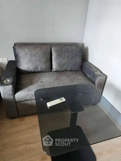 Cozy living room with modern gray sofa and sleek glass coffee table, perfect for relaxation.