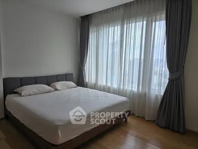 Spacious bedroom with large window and elegant curtains, perfect for natural light lovers.