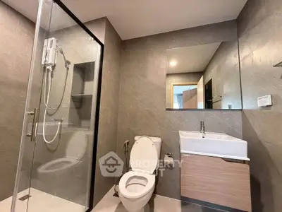Modern bathroom with glass shower and sleek vanity in contemporary apartment.