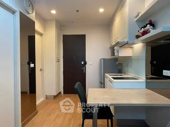 Modern kitchen with sleek cabinetry and dining area in a cozy apartment.