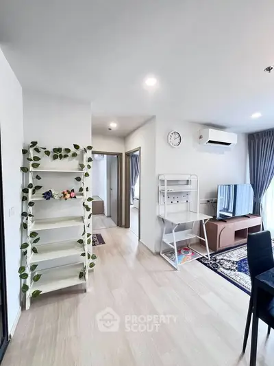 Modern living room with stylish decor, featuring a TV, air conditioning, and elegant shelving in a bright, airy space.