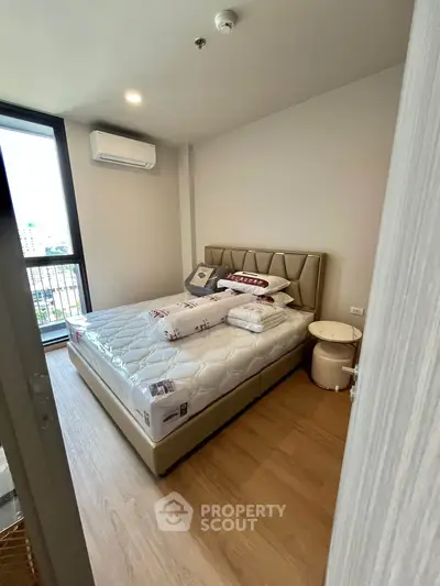 Modern bedroom with stylish decor and city view, featuring a comfortable bed and air conditioning.