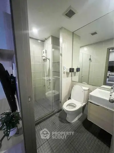 Modern bathroom with glass shower and sleek fixtures in contemporary apartment.