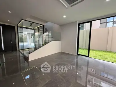 Modern interior with sleek staircase and large windows overlooking a green garden.