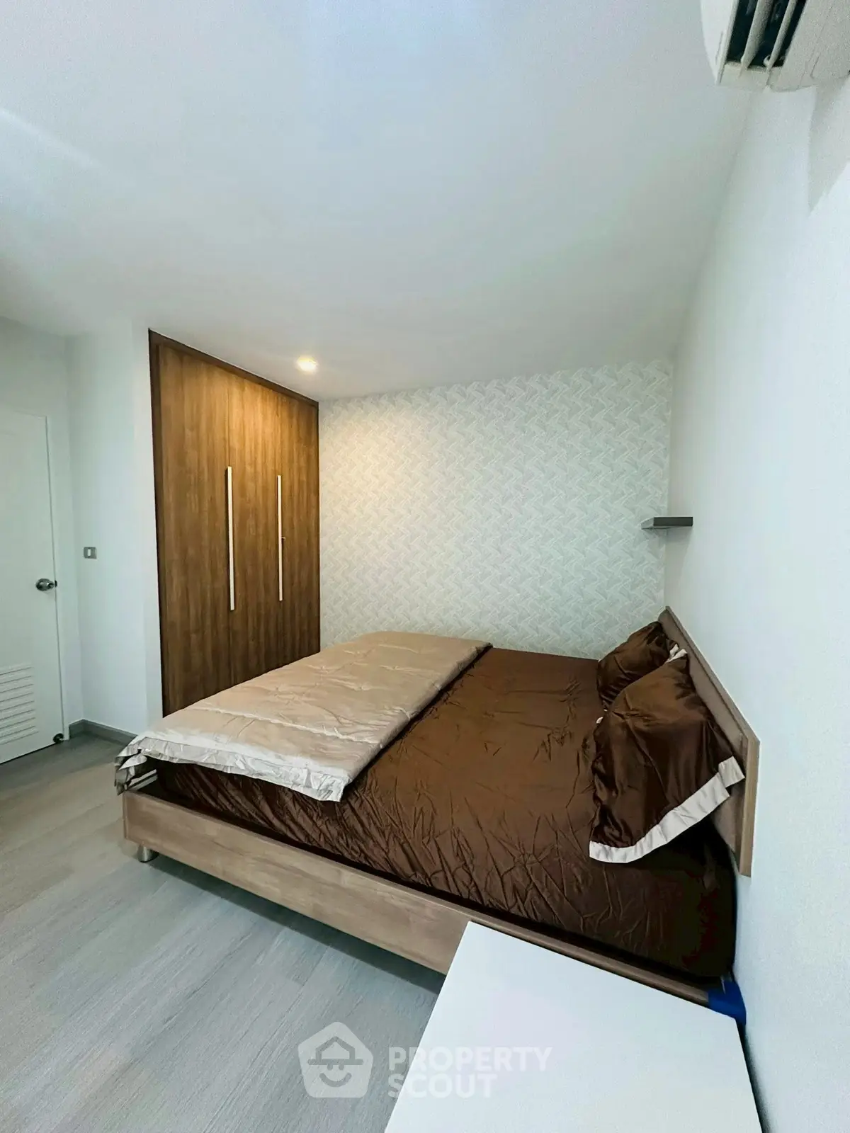 Modern bedroom with stylish wooden wardrobe and cozy bedding in a contemporary apartment.