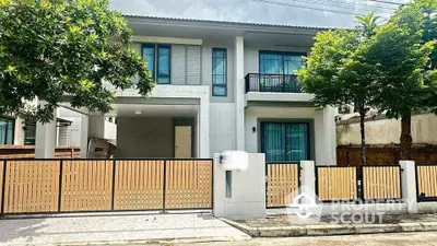 Modern two-story house with gated entrance and lush greenery