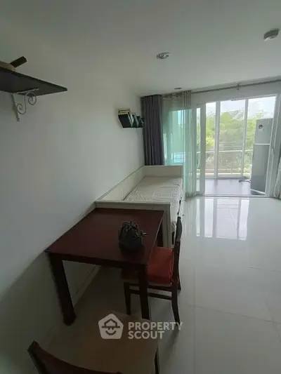 Bright living room with modern furniture and large windows leading to a balcony.