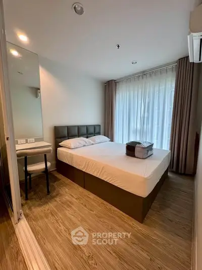 Modern bedroom with large window and stylish decor in a cozy apartment.