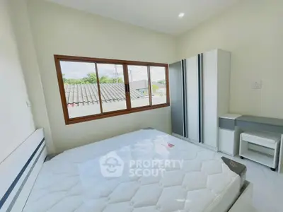 Bright bedroom with large window and modern furniture, offering a serene and airy atmosphere.