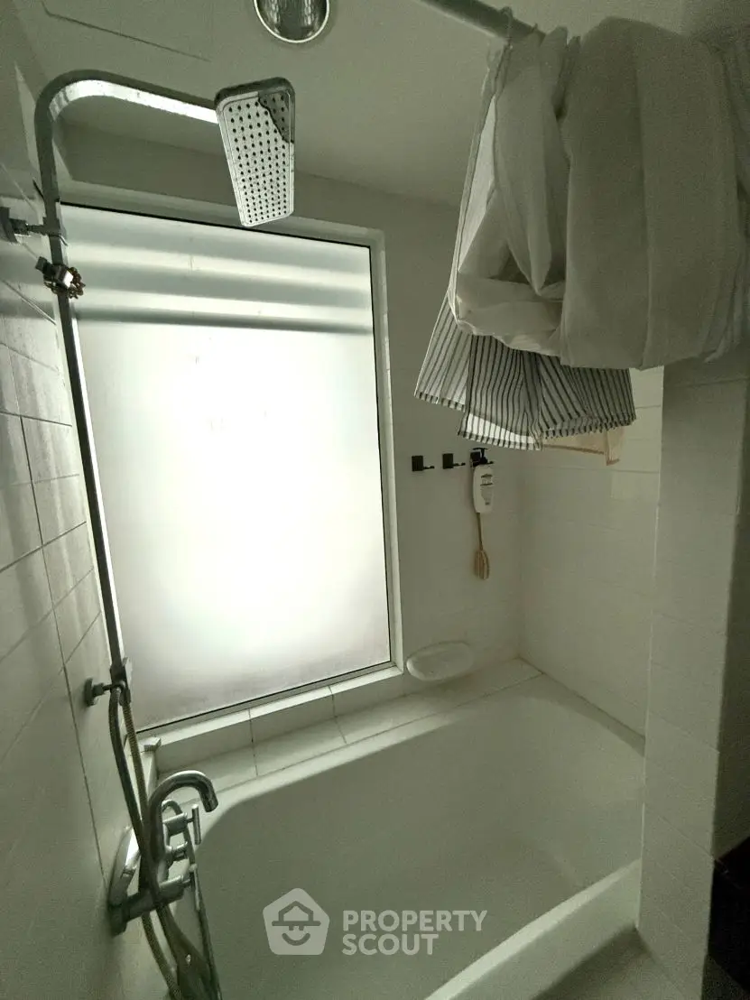 Modern bathroom with frosted window and overhead shower in sleek design.