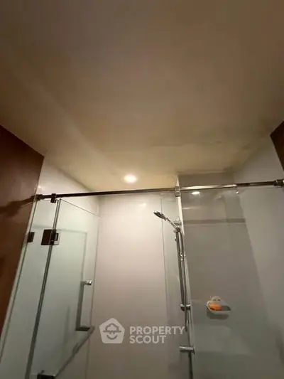 Modern bathroom with glass shower enclosure and recessed lighting.