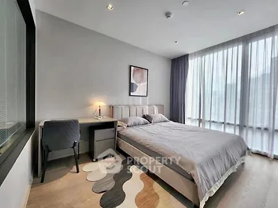 Modern bedroom with large window and stylish decor in a contemporary apartment.