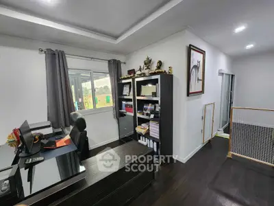 Modern home office with sleek desk and bookshelf, dark wood flooring, and natural light.