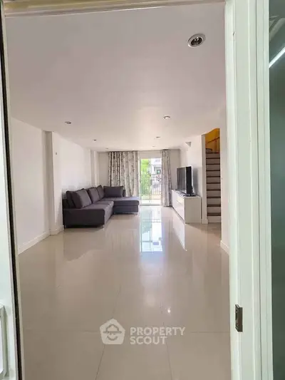 Spacious modern living room with sleek tile flooring and large sectional sofa, perfect for relaxation.