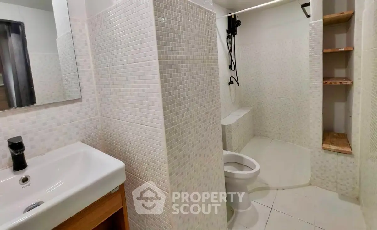 Modern bathroom with sleek fixtures and tiled walls, featuring a shower and toilet.