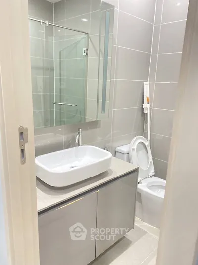 Modern bathroom with sleek fixtures and neutral tiles, featuring a stylish vanity and mirror.
