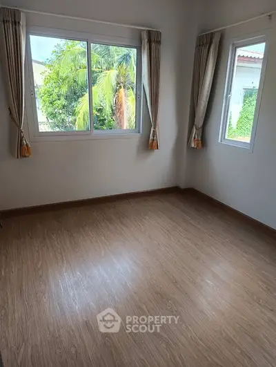 Bright empty room with large windows and wooden flooring, ideal for customization.