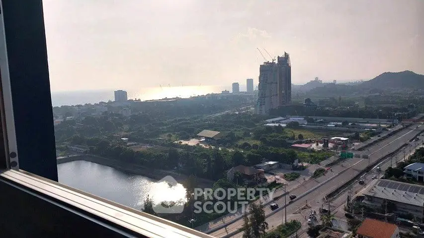 Stunning cityscape view from high-rise building with ocean horizon and lush greenery.