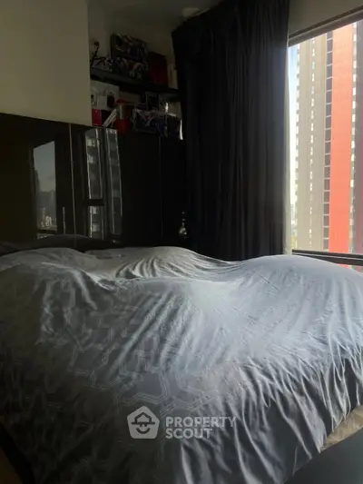 Cozy bedroom with large window and modern decor in urban apartment.