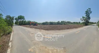 Expansive land plot at a prime corner location, ideal for development with clear skies and lush surroundings.