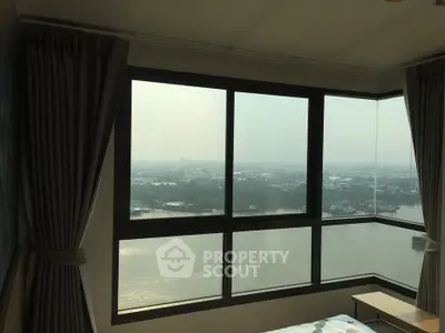Stunning high-rise bedroom with panoramic river view and large windows.