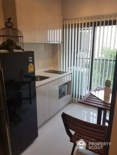 Modern compact kitchen with sleek cabinetry and dining area overlooking greenery