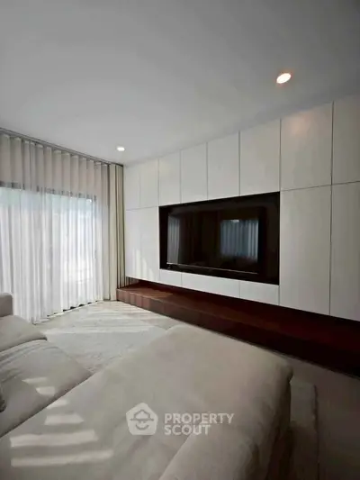 Modern living room with sleek built-in entertainment center and large window.