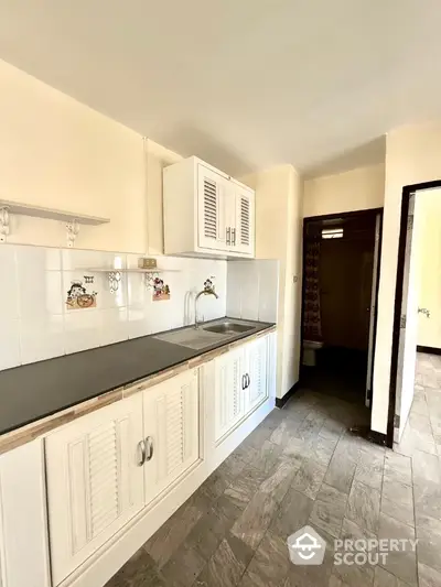 Charming kitchen with white cabinetry and tiled backsplash in cozy apartment