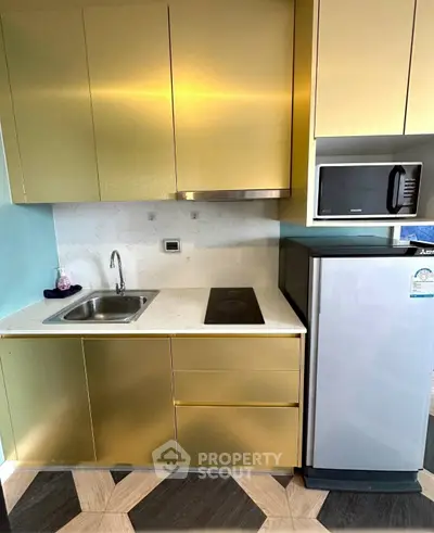 Modern compact kitchen with gold cabinets, microwave, and fridge
