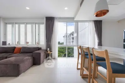 Modern living room with large windows and stylish furniture, offering a bright and inviting atmosphere.