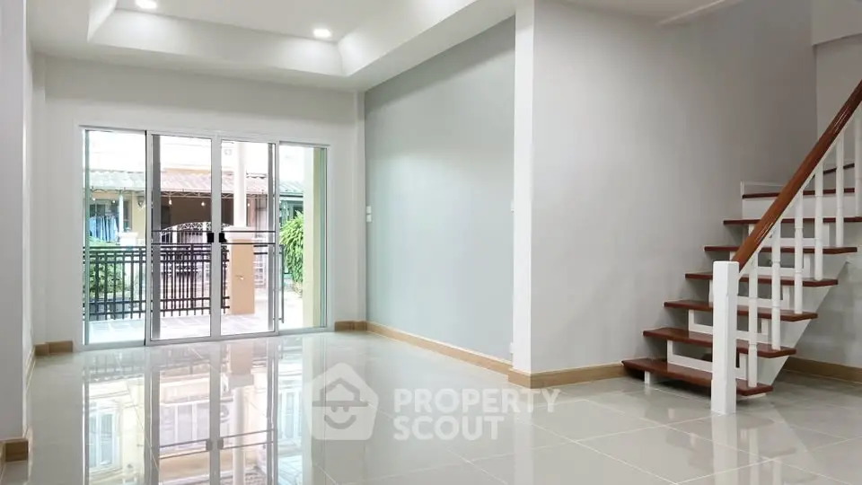 Spacious modern living room with sleek staircase and large windows for natural light.
