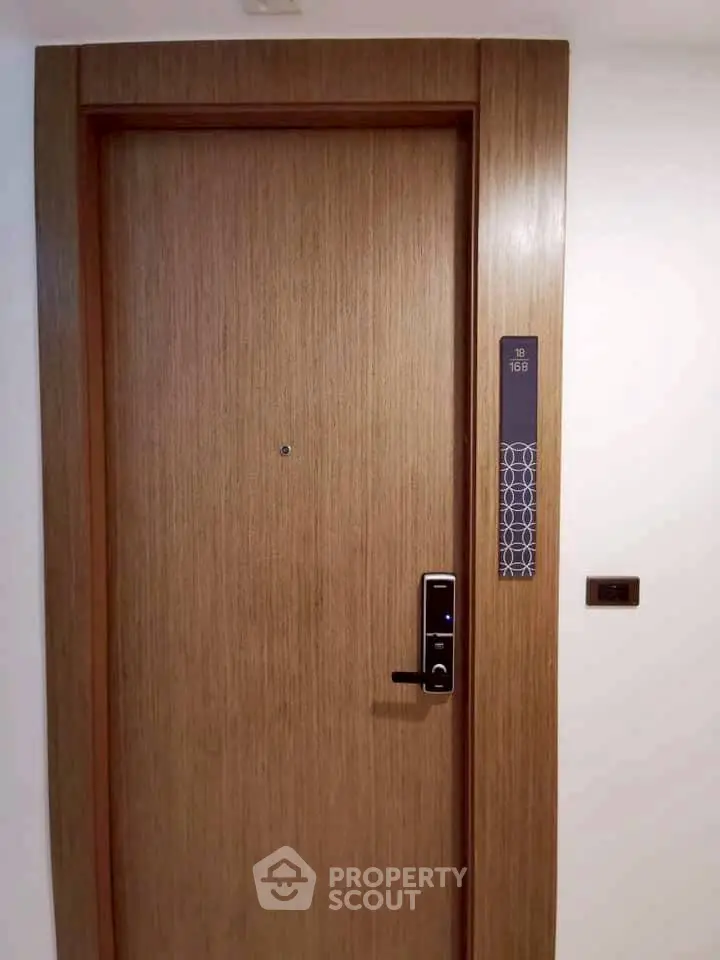 Modern apartment entrance with electronic lock and sleek wooden door design.