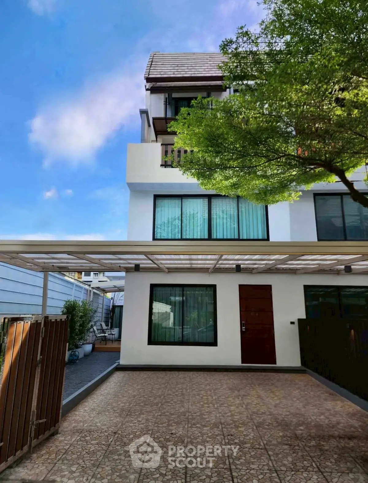 Modern three-story townhouse with spacious driveway and lush greenery, perfect for urban living.
