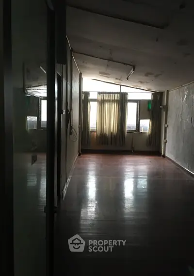 Spacious empty room with wooden floors and large windows, ideal for customization.